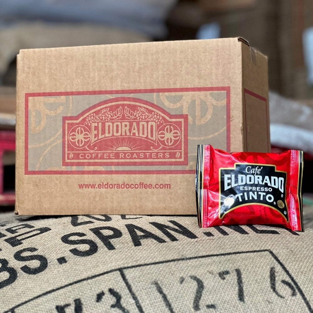 Cardboard box filled with El Dorado Coffee Roasters Espresso Tinto coffee rests on a burlap coffee bean sack.