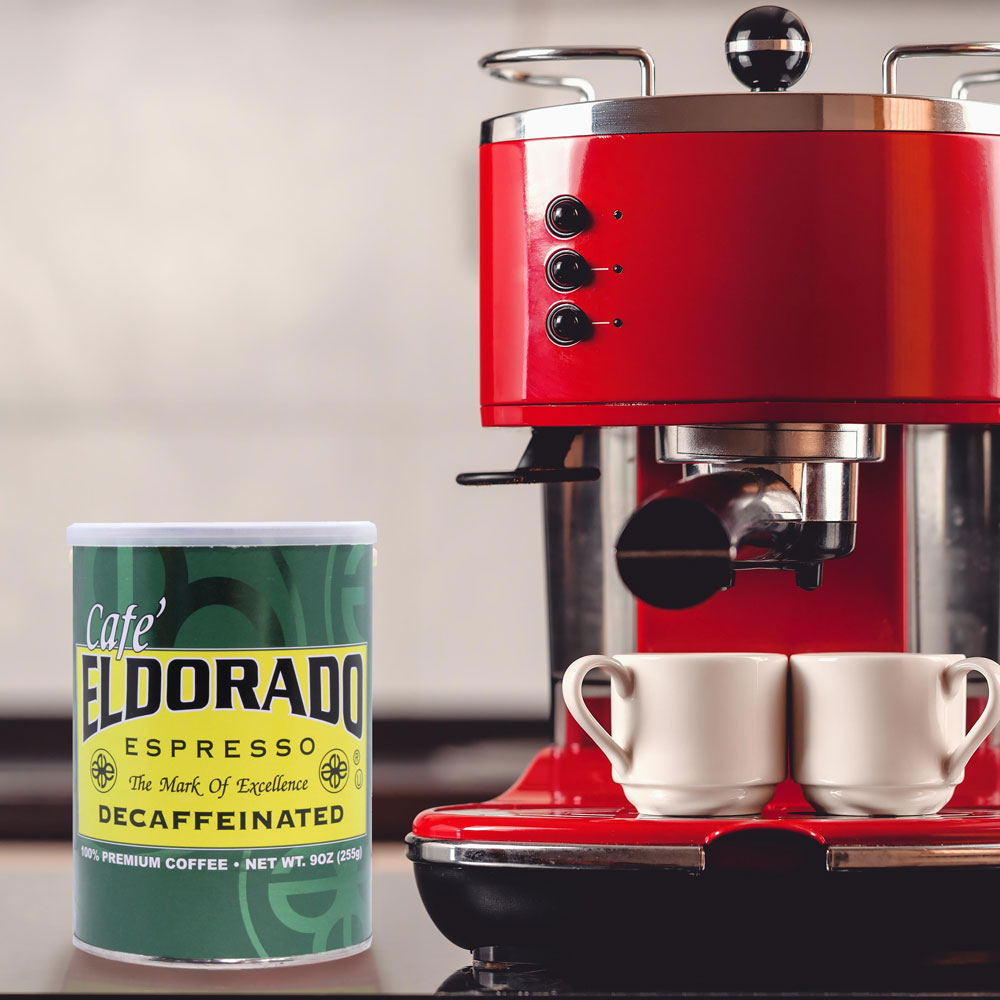 Red espresso machine brews Cafe Eldorado decaffeinated espresso into two white cups.