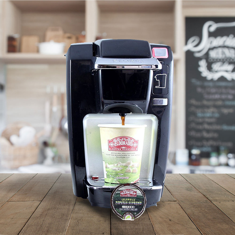 Black Keurig coffee maker brews El Dorado Colombian Popayan Supremo coffee into a to-go cup.