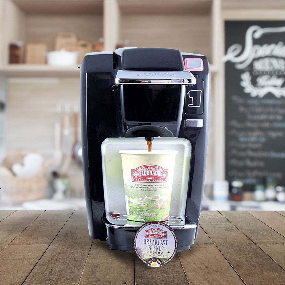 Black Keurig K-Cup coffee maker brewing a cup of Eldorado Breakfast Blend coffee into a to-go cup.