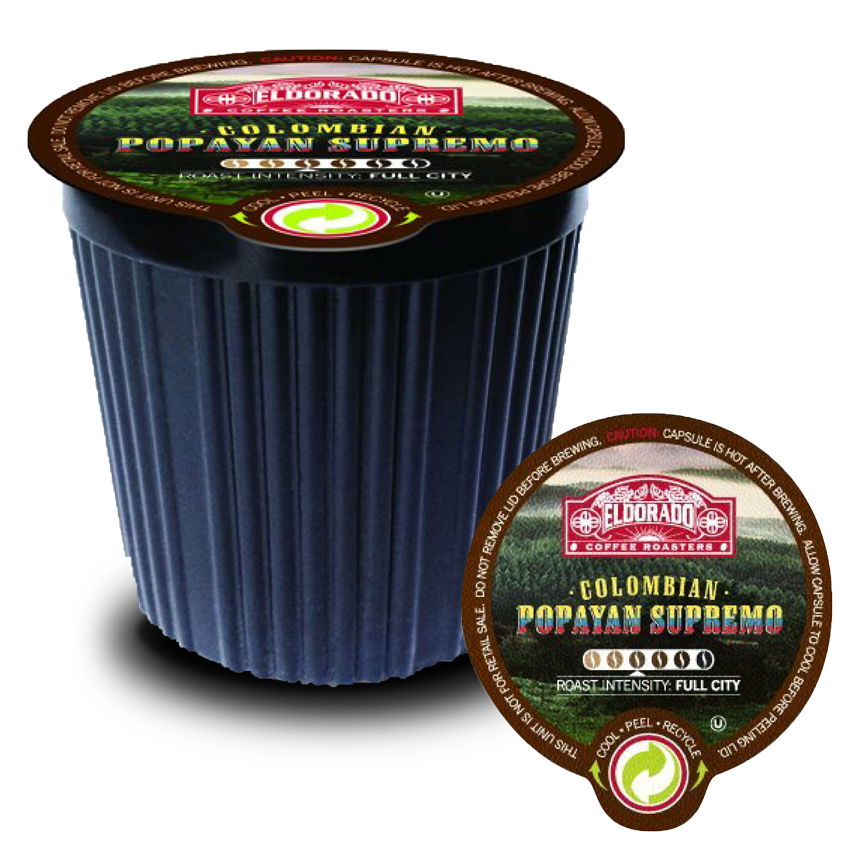 A black single-serve coffee pod filled with Eldorado Coffee Roasters Colombian Popayan Supremo coffee sits on a white background with a peeled foil lid beside it. 

