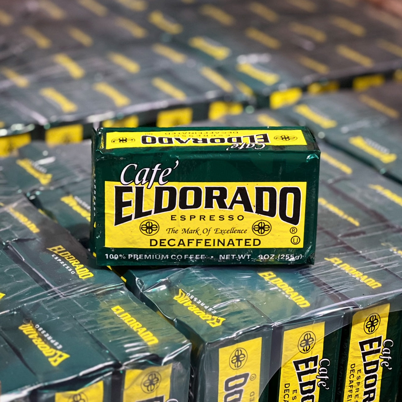A green and yellow box of Cafe Eldorado decaffeinated espresso coffee sits atop a stack of more boxes. 

