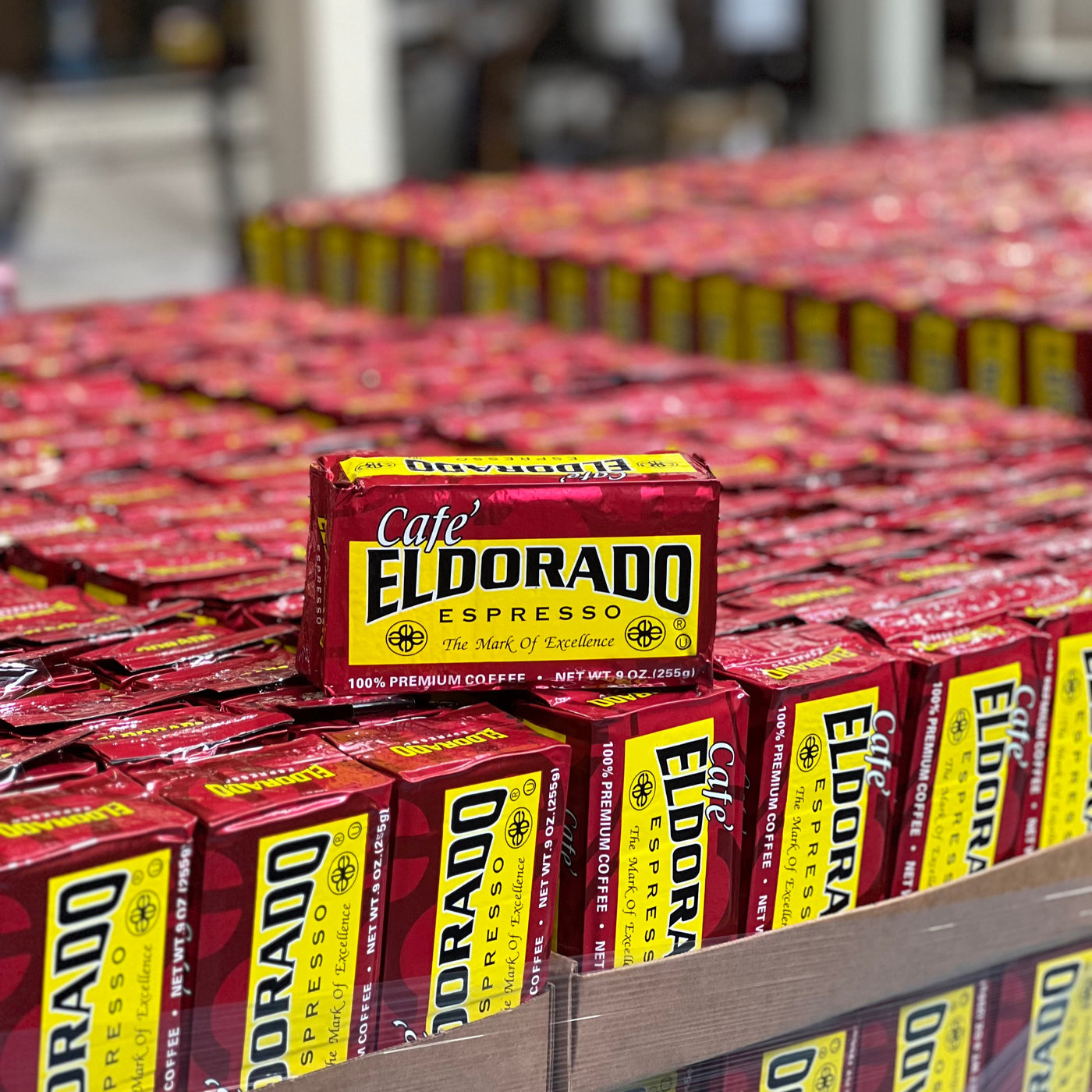 A stack of Cafe El Dorado Espresso coffee bags sits on a pallet, ready for distribution. 
